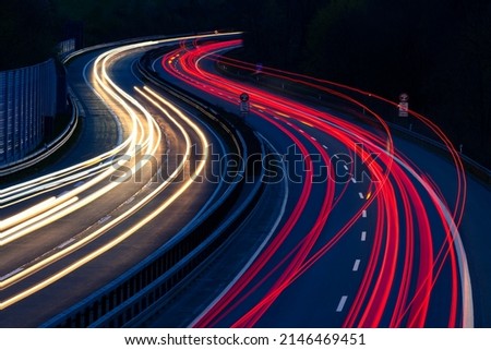 German Autobahn A46 at blue hour dusk twilight in Iserlohn from a street bridge. Long time exposure with light traces of passing car lights in motion. Bent double or twin curve froming an S-line.