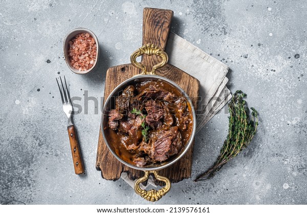 German braised beef cheeks in brown red wine sauce.\
Gray background. Top\
view.