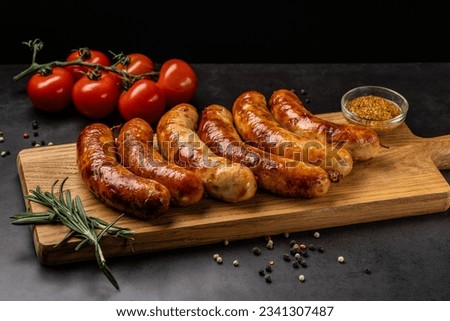 German cuisine. Juicy fried chicken, beef and pork sausages lie on a wooden board, on a black background.