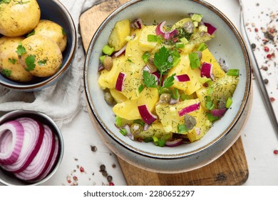 German cuisine. Potato salad with red onions and olive oil in a bowl on a white background. Top view. - Powered by Shutterstock