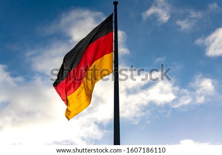German Flag in black-red-gold colors on a sunny day in german capital Berlin near the Reichtstag Building is the national Symbol of the Bundesrepublik Deutschland