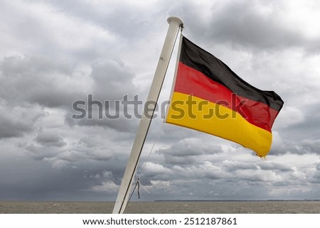 Similar – Waving German flag in front of a blue sky with clouds, Hallig Oland in the background