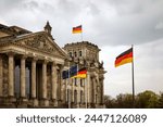 The German flag waves at the Bundestag, the building of the German parliament. Cloudy sky