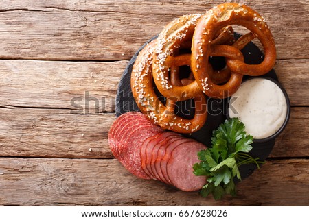 German food: sliced sausages and pretzels with cream sauce close-up on the table. horizontal view from above
