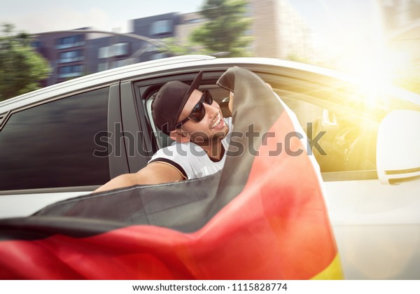 German\
football fan waving a flag out of a car\
window