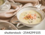 German Frisian north sea brown shrimp soup with dill, potato, leak and lemon in porcelain cup with silverware spoon on festive tablecloth and wooden background 