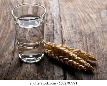 German hard liquor Korn Schnapps in shot glass with wheat ears on rustic wooden table