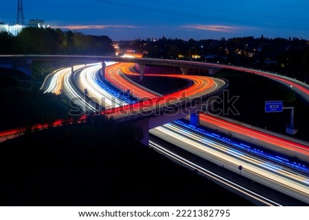 German Motorway in Bochum-Wattenscheid. Streets and bridges at dusk with light traces of passing fast cars and emergeny blue lights. The “Ruhrschnellweg“ or A40 is the main highway in Ruhr Basin.