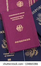 A German passport resting on a stack of American and German passports.