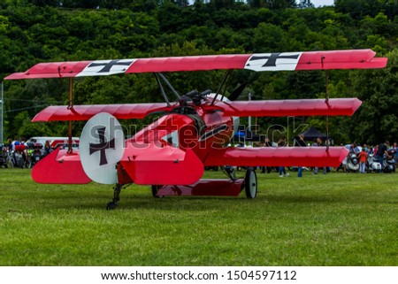 German, red triplane replica on a meadow.