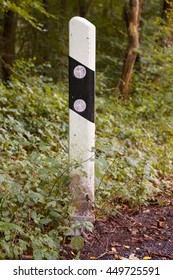 German road boundary pillar at the edge of the forest