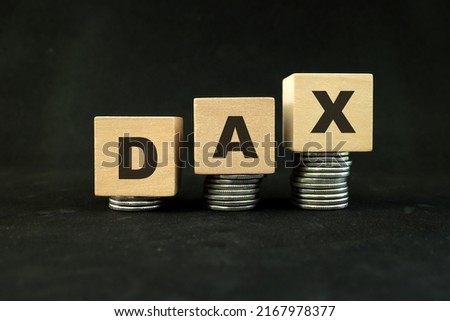 German stock market, Germany economy growth and recovery concept. DAX index in wooden blocks with increasing stack of coins in black background.