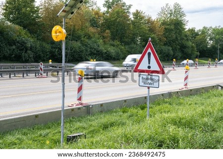 German Triangle Sign with Exclamation Mark: Construction Site Exit, Cars in Background