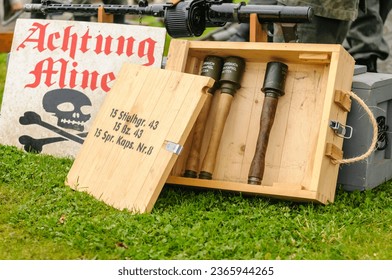 German warning sign with skull and crossbones saying "achtung" (tr: warning) for "minen"
					 (tr: mines) and a box of stick grenades.