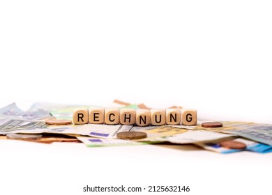 German Word For Invoice, RECHNUNG, Spelled With Wooden Letters Wooden Cube On A Plain White Background With Banknotes And Coins, Concept Image