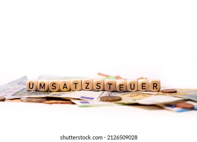 German Word For Sales Tax, UMSATZSTEUER, Spelled With Wooden Letters Wooden Cube On A Plain White Background With Banknotes And Coins, Concept Image