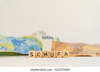 German Word For Schufa, SCHUFA, Spelled With Wooden Letters Wooden Cube On A Plain White Background With Banknotes, Concept Image 