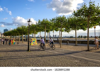 Düsseldorf / Germany - 12 August 2019: Two People Cycling In Downtown Düsseldorf Along The River Rhine Waterfront 