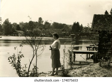 GERMANY -  1960s: An Antique Photo Shows Woman With A Camera Standing On The Shore Of Lake