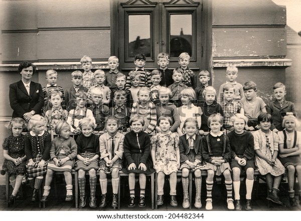 GERMANY, CIRCA 1953 -\
Vintage photo of group of schoolmates and teacher posing in front\
of their school