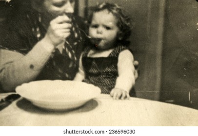 GERMANY, DECEMBER 25, 1938: Mother feeds a little daughter 