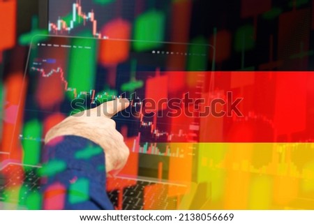 Germany downtrend of the economy in a world crisis. Man hand shows on the decreasing candle stick graph chart in the stock market with the flag on the background, March 2022, San Francisco, USA