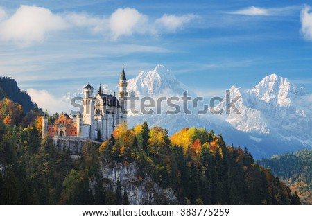 Germany. The famous Neuschwanstein Castle in the background of snowy mountains and trees with yellow and green leaves.