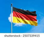 Germany flag flying on blur blue clouds background.