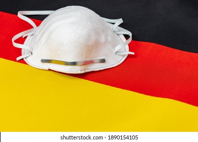 Germany Flag And N95 Face Mask. Concept Of Covid-19 Coronavirus Lockdown, Surge, Travel Ban And Healthcare Crisis