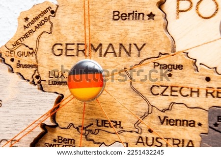 Germany flag on the pushpin with red thread showed the paths of movement or areas of influence in the global economy on the wooden map. Planning of traveling or logistic concept. Network connection. 