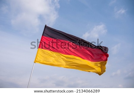 Germany flag waving in the wind close-up against a blue sky. 