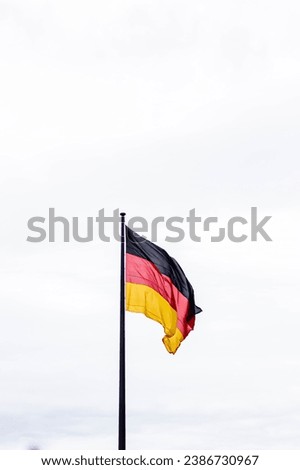 Germany flag waving in the wind close-up against a white sky. German flag on contrasting sky