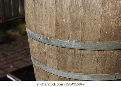 Germany.  Fragment Of An Old Wooden Vine Barrel With An Metall Hoop On A Dark Background. Wooden Barrel With Metall Straps. Wood Texture. Side View. Close-up. Macro. Copy Space