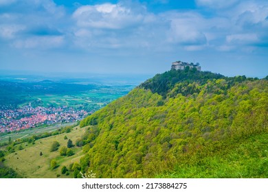 Germany, Hohenneuffen castle ruins on top of a forested mountain in foggy nature landscape atmoshpere in springtime with sun, aerial panorama view above tree tops