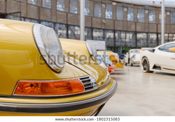 Düsseldorf, Germany - JUNE 2020: Selected focus\
at headlight and hood of yellow vintage luxury Porsche sport car at\
Classic Remise in Düsseldorf,\
Germany..