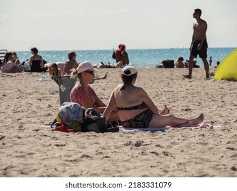 Warnemünde, Germany - June 28, 2022: Two Women Tanning At The Beach In Tourist Hotspot Rostock-Warnemünde