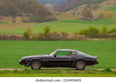 Münsingen, Germany - May 1, 2022: Pontiac Firebird Trans Am american oldtimer vintage luxury sports muscle car on a country road near Münsingen, Germany.