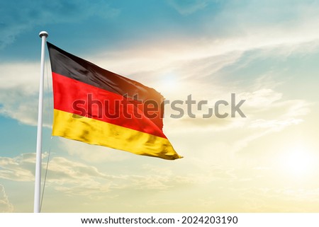 Germany national flag waving in beautiful clouds.
