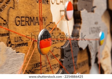 Germany, Poland and Ukraine flags on the pushpin with red thread showed the paths of movement or areas of influence in the global economy on the wooden map. Planning of traveling or logistic concept