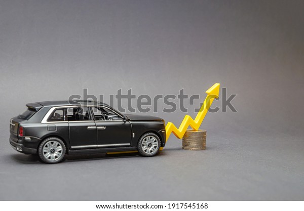 Germany.Hamburg 01.02.2021.Editorial.Rising car\
prices. On a black background, there is a model car with a yellow\
arrow pointing upwards. Copy\
space.