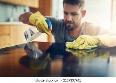 Germs, aint nobody got time for that. Shot of a young man cleaning the kitchen counter at home.