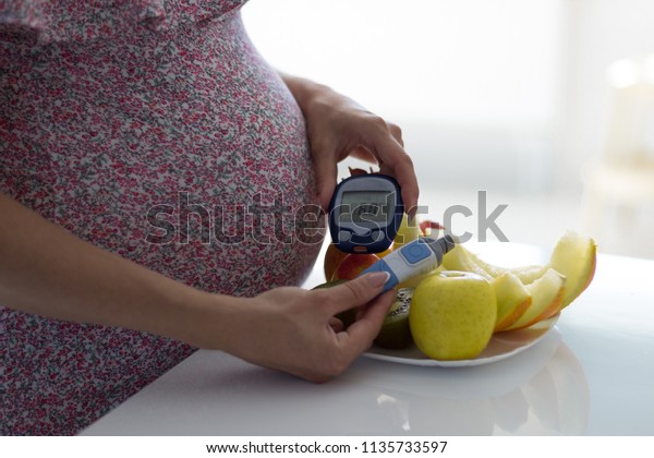 Gestational diabetes mellitus, diet of a
pregnant patient with diabetes mellitus. Measurement of blood sugar
level of a pregnant woman with a
glucometer