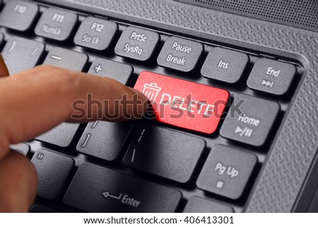 Gesture of a hand finger pressing DELETE on a laptop keyboard