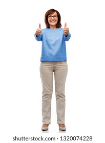 gesture and old people concept - smiling senior woman in glasses showing thumbs up over white background