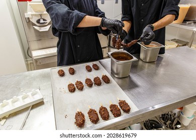 Gesture of the profession of two pastry chefs in uniform, who make ice cream. The production of dark chocolate and milk ice cream flavors. Manual preparation of creamy French ice cream. 