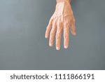 The gesture of rough hands and wrinkles of the elderly on a gray background.