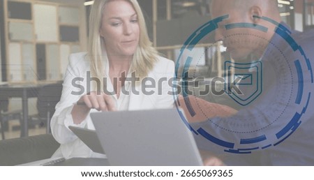 Gesturing colleagues in white and dark jackets viewing laptop in office lounge with overlay. Collaboration, teamwork, modernoffice, digitalinterface, professional, innovation, coworking