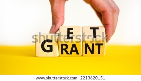 Get grant symbol. Businessman turns wooden cubes with concept words Get grant on a beautiful yellow table white background. Copy space. Business and get grant concept.