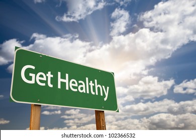 Get Healthy Green Road Sign With Dramatic Clouds, Sun Rays And Sky.