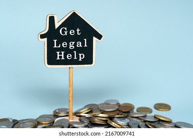 Get Legal Help Text On Wooden House With Pile Of Coins Against Blue Background.. Business, Finance, Money Management, Property Loan Or Mortgage And Auction Concept.